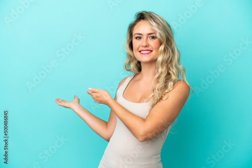 Young Brazilian woman isolated on blue background extending hands to the side for inviting to come