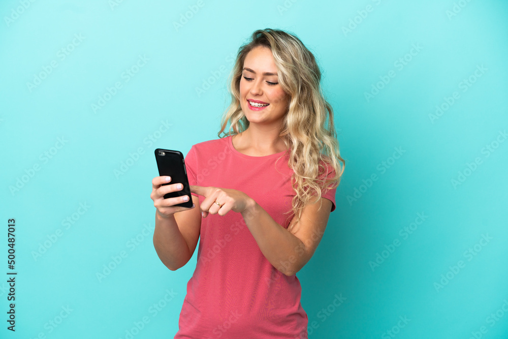 Young Brazilian woman isolated on blue background sending a message or email with the mobile Young Brazilian woman isolated on blue background sending a message or email with the mobile