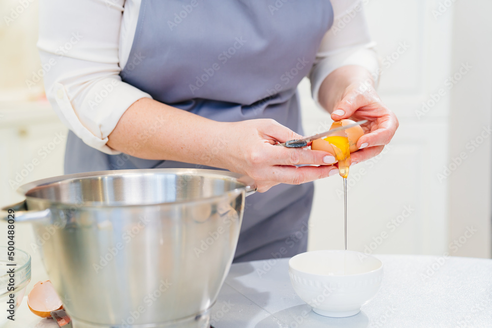A woman breaks an egg and separates yolks from proteins A woman breaks an egg and separates yolks from proteins