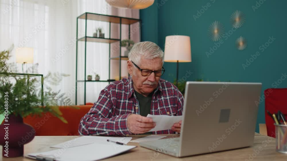 Angry bored upset elderly grandfather throws out household bills bank loan domestic expenditures payment, paperwork. Senior old man use laptop, e-bank online app on computer, manage family finances Angry bored upset elderly grandfather throws out household bills bank loan domestic expenditures payment, paperwork. Senior old man use laptop, e-bank online app on computer, manage family finances