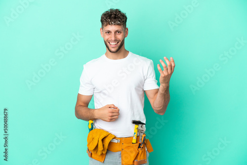 Young electrician blonde man isolated on green background making guitar gesture