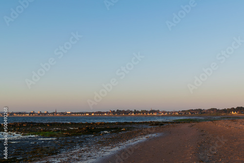 Beautiful color of sky in evening at beach before sunset. Landscape of town next to coast line, mountain, water, land, sand. Freshness and mindful. Nature scenery