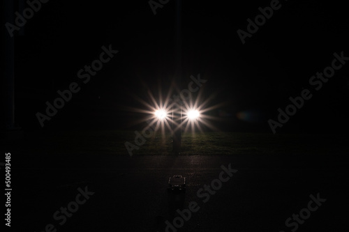 car headlights in a starburst shape form a backlight for a skateboard in the dark of the night