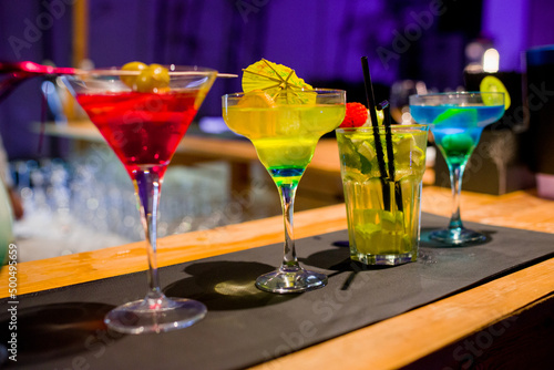 A row of different martini glasses on the counter in a bar