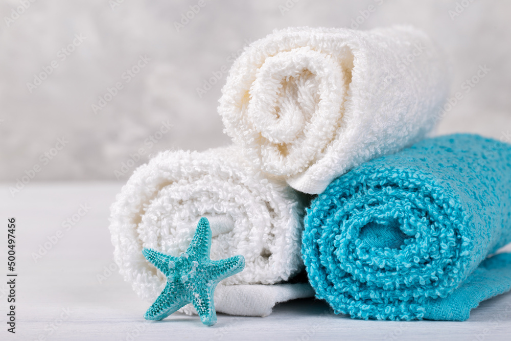 Spa composition with white and blue soft rolled cotton towels and star fish copy space Spa composition with white and blue soft rolled cotton towels and star fish copy space
