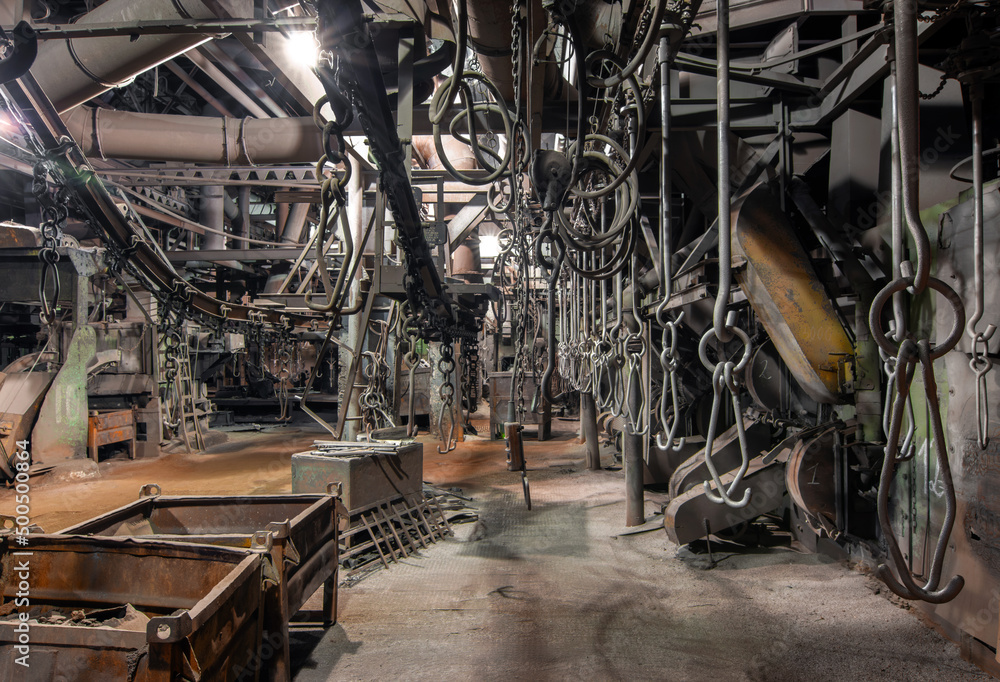 Interior of an old bankrupt factory. Stopped overhead conveyor with hooks for fastening parts