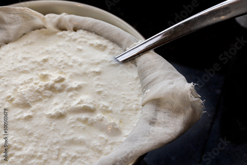 Homemade yogur being processed through cheesecloth to drain whey
