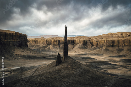 Photos A dark tower of black shale rock rises up among cliffs of the Utah desert as dark clouds roll in, making the landscape look moody and evil