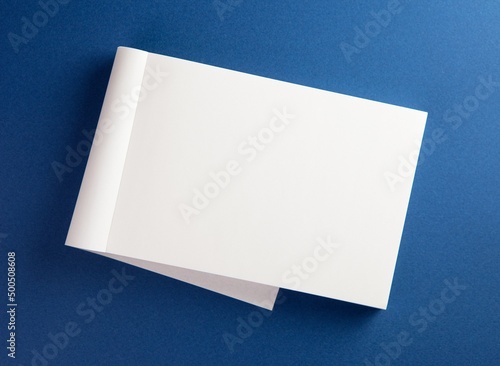Blank memo pad with page folded back on blue surface. photo