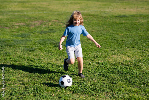 Soccer kid boy playing football. Child boy play football on outdoor field. Children score goal at soccer game. Cute boy kicking soccer ball.