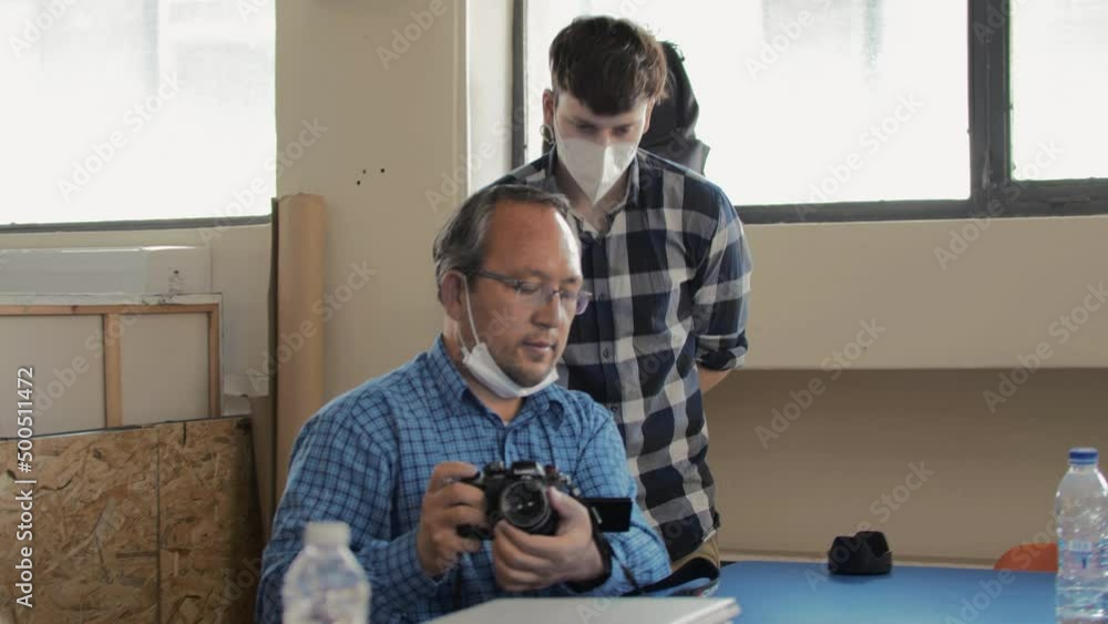 Young man teaching mature student camera skills Young man teaching mature student camera skills