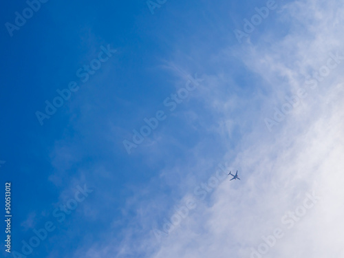 Beautiful blue sky with little silhouette airplane flying. Concept of transportation.