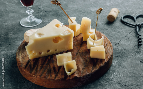 Piece of cow's milk Maasdam cheese on wooden cutting board over concrete background. photo