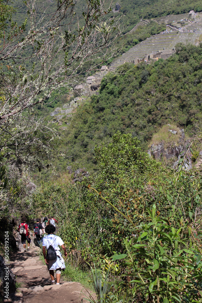 Turistas caminham no alto do Huayna Picchu, ao fundo vista das ruinas de Machu Picchu