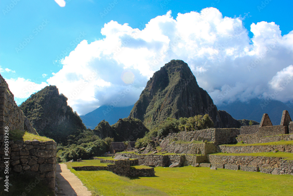 Monte Huayna Picchu, e em primeiro plano gramado e vista parcial das ruinas incas de Machu Picchu - obrazy, fototapety, plakaty 