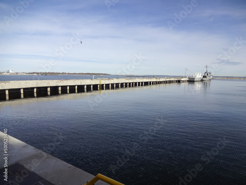 Seascape in early morning to stone pier with old boats moored. Ripple on navy water and blue sky. Noblessner, Tallinn, Estonia, Europe. April 2022