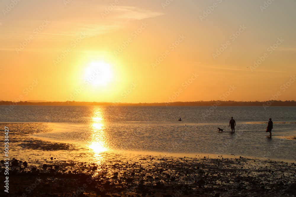 Low tide at Victoria Point. Families walking home and children playing as the sun sets Low tide at Victoria Point. Families walking home and children playing as the sun sets