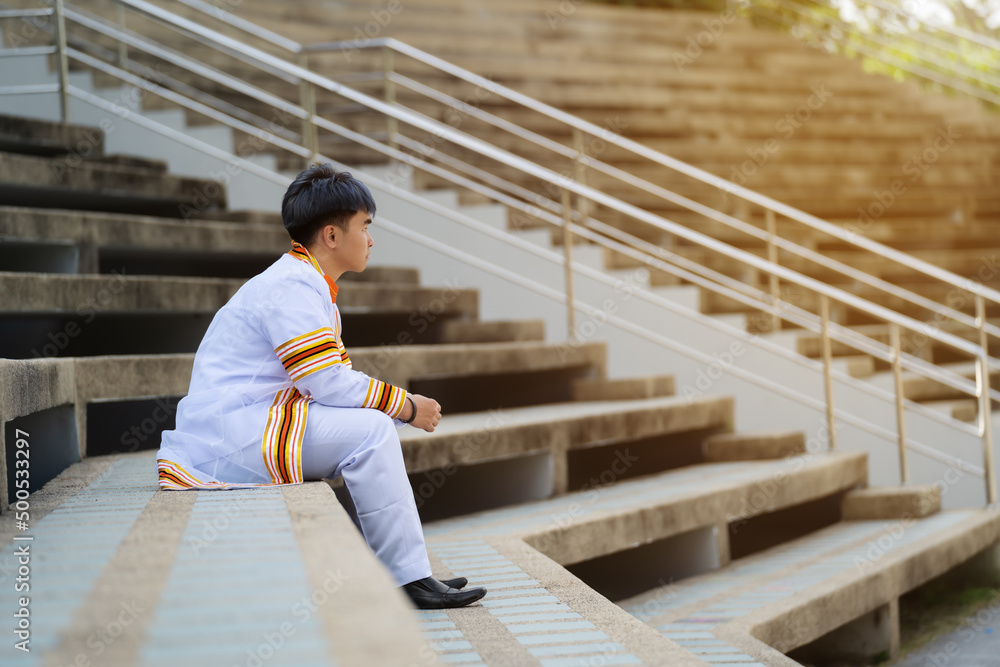 man university graduates in graduation gown sitting on stairs man university graduates in graduation gown sitting on stairs