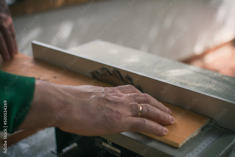 Hands Of A Man Making Custom Furniture Wood Parts On Machine Tool Called Table Saw In Woodworking Shop. Wood Production Concept. Detail Hands Of A Man Making Custom Furniture Wood Parts On Machine Tool Called Table Saw In Woodworking Shop. Wood Production Concept. Detail