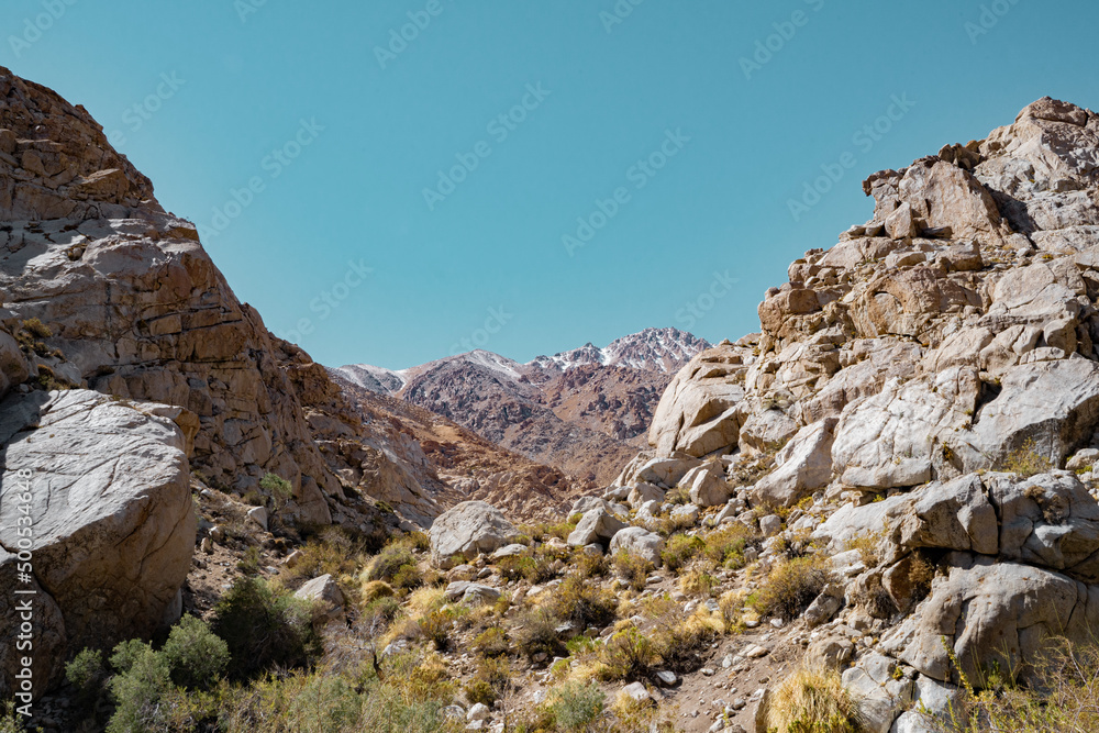 Horizontal shot of a rocky valley with snow-capped mountains in the background, Chile