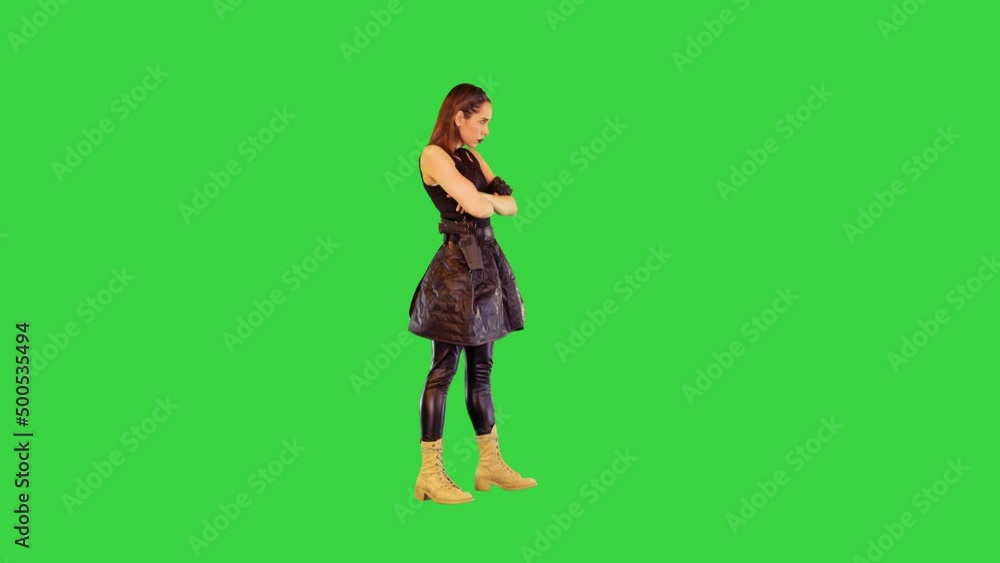 Game-character girl with a gun on belt stands folding her arms in threatening manner on a Green Screen, Chroma Key. Game-character girl with a gun on belt stands folding her arms in threatening manner on a Green Screen, Chroma Key.