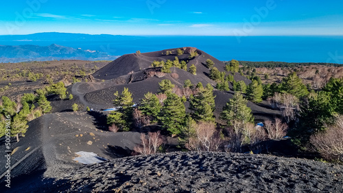 Scenic view on crater of Sartorio on volcanic landscape of volcano mount Etna, in Sicily, Italy, Europe. Solidified lava, ash, pumice fields of erupted crater. Bare terrain with view in Ionian sea photo