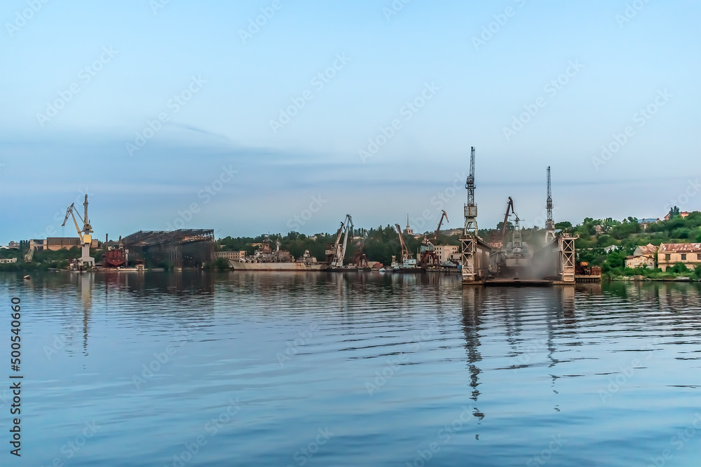 Mykolaiv, Ukraine - July 25, 2020: Industrial coastline with the Mykolayiv Shipyard on the Inhul River on a summer evening. Urban panorama of Ukrainian town