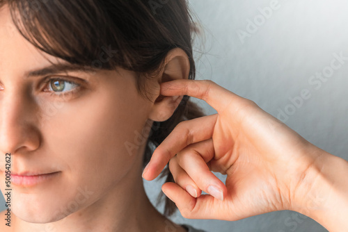 Woman putting a finger into her ear. Itchy ear isolated with copy space. otitis media