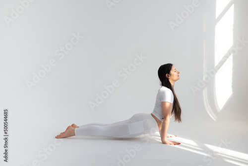 девушка на белом фоне в позе «собаки, смотрящей вверх» (Урдхва Мукха Шванасана)
a girl on a white background in the pose of a 