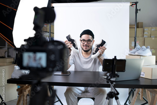 Young attractive Asian man blogger or vlogger looking at camera reviewing product. Modern businessman using social media for marketing. Business online influencer on social media concept. photo