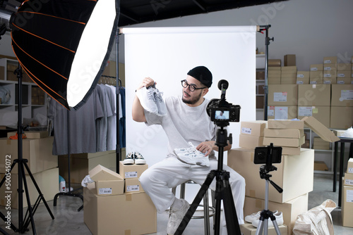Young attractive Asian man blogger or vlogger looking at camera reviewing product. Modern businessman using social media for marketing. Business online influencer on social media concept. photo
