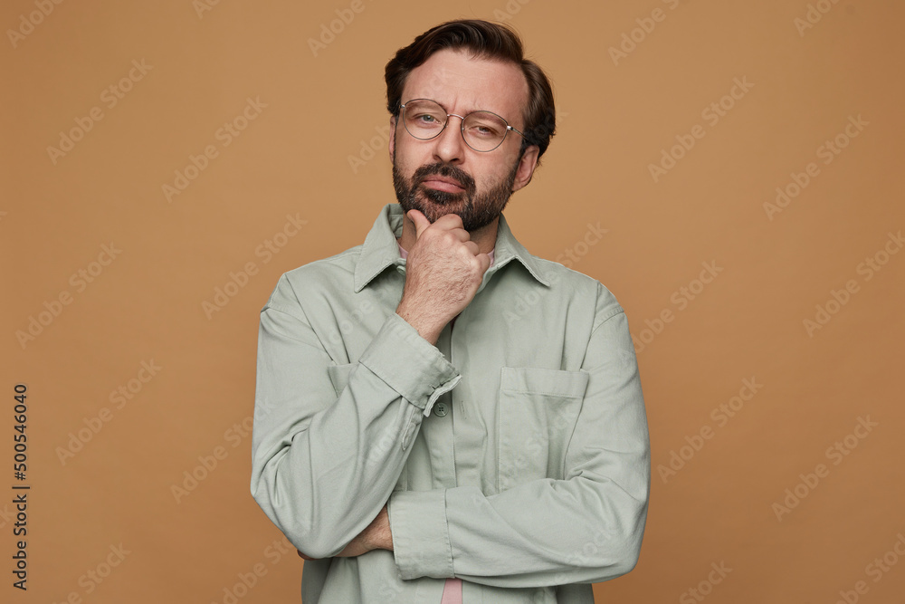 studio portrait of bearded man posing over beige background looking aside with serious facial expression studio portrait of bearded man posing over beige background looking aside with serious facial expression