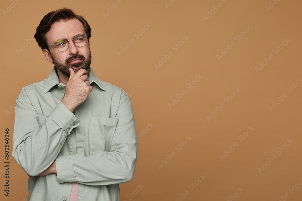 studio portrait of bearded man posing over beige background looking aside with sad facial expression studio portrait of bearded man posing over beige background looking aside with sad facial expression