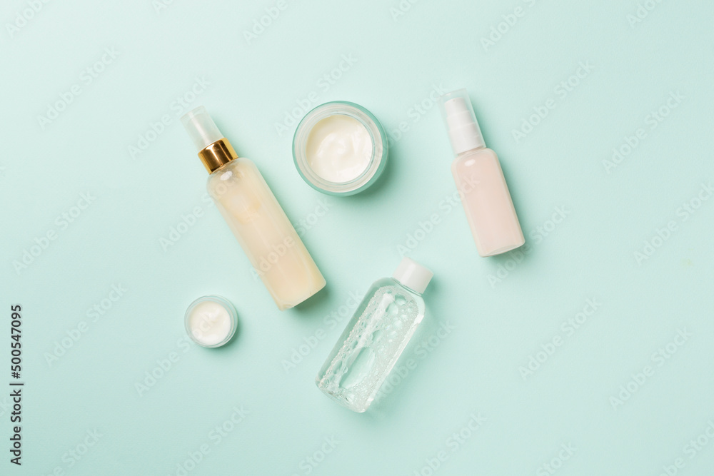 Different cosmetic bottles on color background, top view Different cosmetic bottles on color background, top view