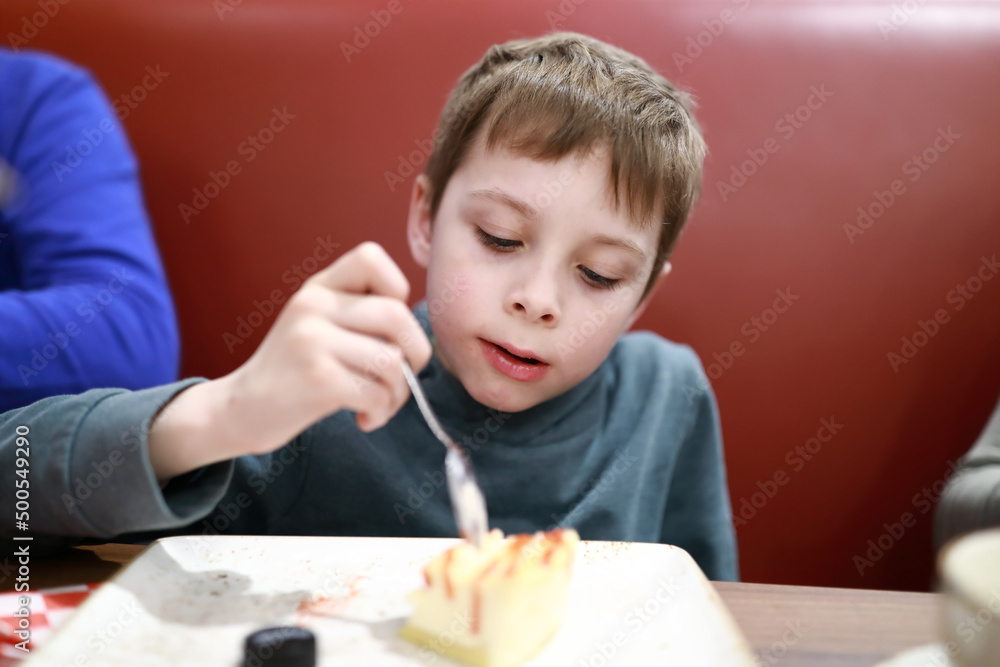 Boy eating cheesecake in restaurant Boy eating cheesecake in restaurant