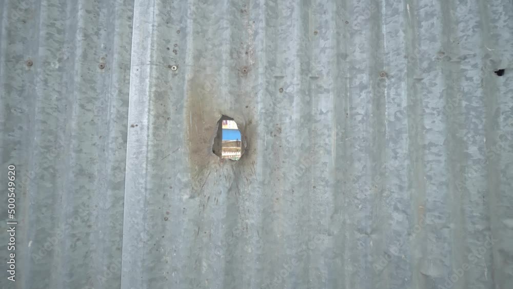 metal fence on construction site in which hole or hole is visible. Movement of camera from the fence. Replacing background or copying a place to replace. copy space. Construction and advertising. metal fence on construction site in which hole or hole is visible. Movement of camera from the fence. Replacing background or copying a place to replace. copy space. Construction and advertising.