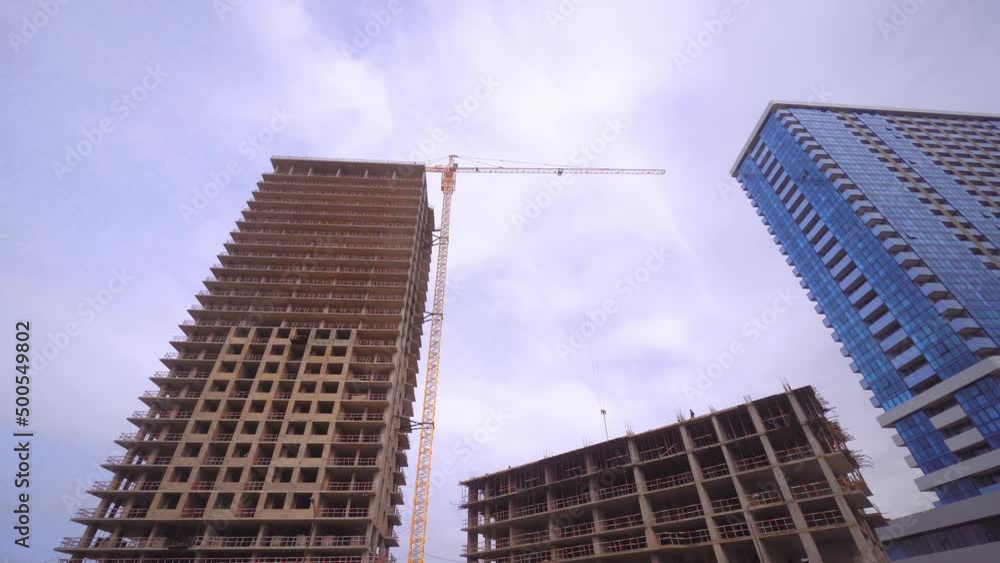 Construction site with high-rise cranes. Construction of modern apartment buildings and new residential complex. Blue sky. Panorama of building under construction and finished residential building.