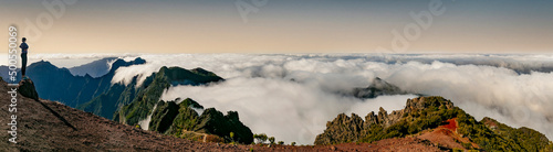 Hiking activity in Madeira island rocky mountains. Trail for Pico Ruivo highest point passing in the clouds . Girl looking at view
