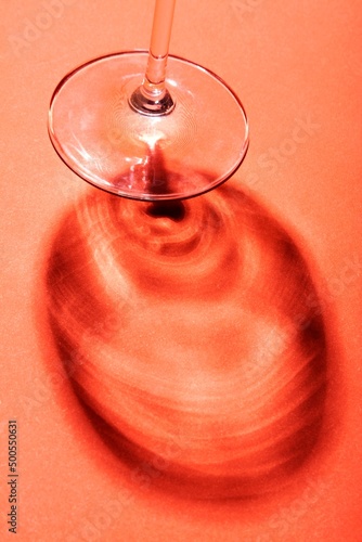 Minimalist still life, wine glass on red background with creative shadow.