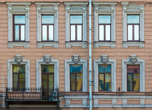 Balcony and many windows in a row on the facade of the urban historic apartment building front view, Saint Petersburg, Russia 