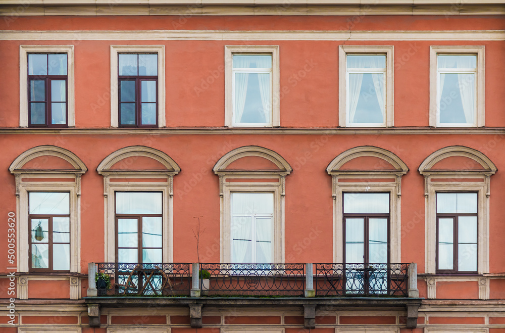 Obraz premium Balcony and many windows in a row on the facade of the urban historic apartment building front view, Saint Petersburg, Russia 