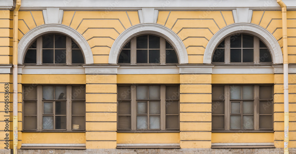 Fototapeta premium Three windows in a row on the facade of the urban historic apartment building front view, Saint Petersburg, Russia 