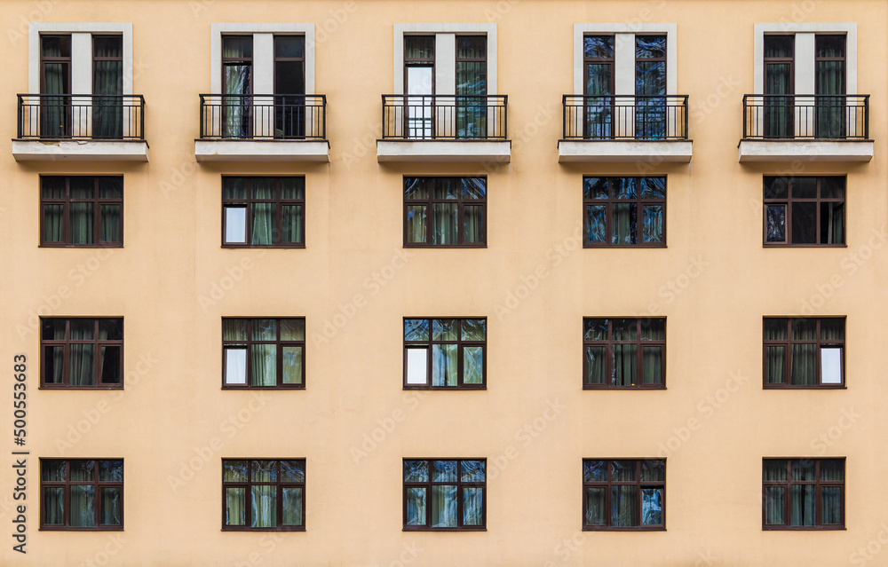 Balconies and many windows in a row on the facade of the modern urban apartment building front view, Krasnaya Polyana, Sochi, Krasnodar Krai, Russia
