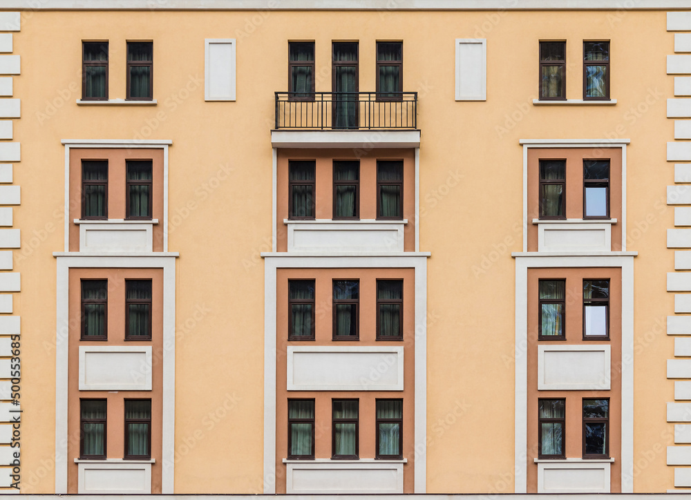 Fototapeta premium Balcony and many windows in a row on the facade of the modern urban apartment building front view, Krasnaya Polyana, Sochi, Krasnodar Krai, Russia 