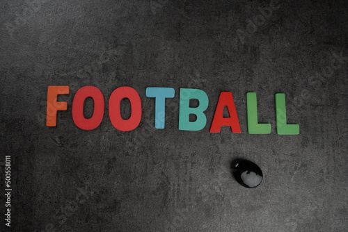 Football word spelled on a black reflective textured background in a studio lighting setup