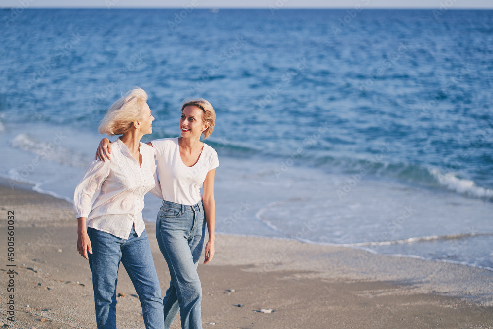 © luengo_ua - Outdoor portrait of smiling happy caucasian senior mother with her adult daughter hugging and walking on sea beach. © luengo_ua - Outdoor portrait of smiling happy caucasian senior mother with her adult daughter hugging and walking on sea beach.