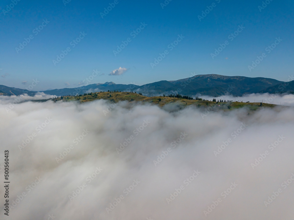 Flight over fog in Ukrainian Carpathians in summer. Mountains on the horizon. A thick layer of fog covers the mountains with a continuous carpet. Aerial drone view. Flight over fog in Ukrainian Carpathians in summer. Mountains on the horizon. A thick layer of fog covers the mountains with a continuous carpet. Aerial drone view.