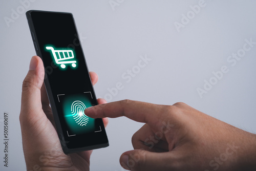 man hand hold smartphone, tablet, cell phone with shopping cart icon on screen and scan finger print on mobile phone. Online shopping technology concept. 