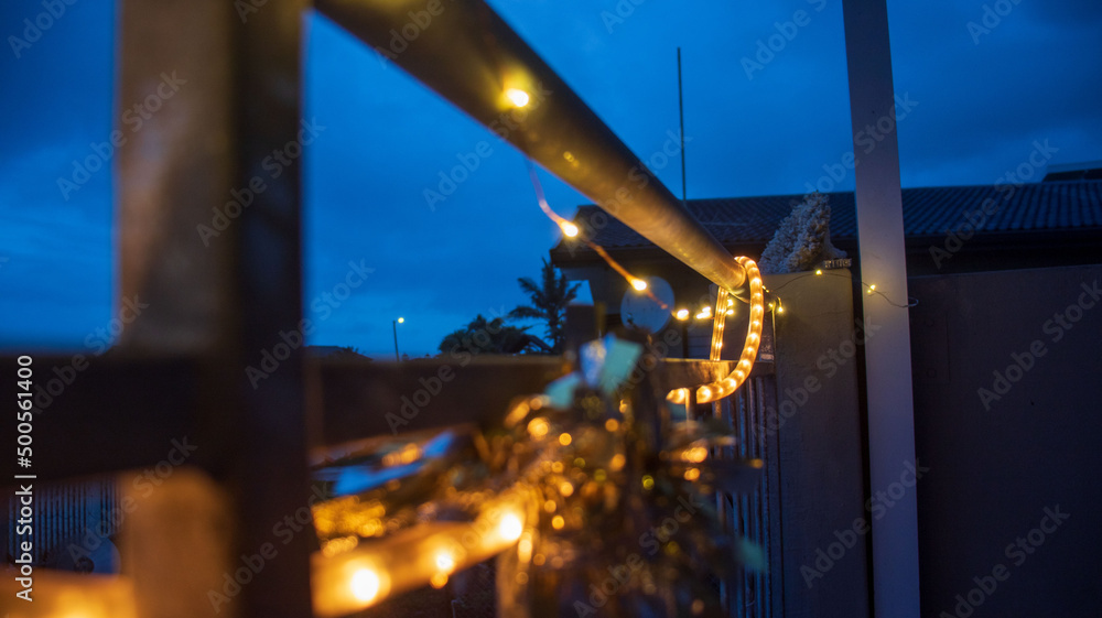 Fototapeta premium A string of lights hanging on a railing connected to a patio with dark blue skies 