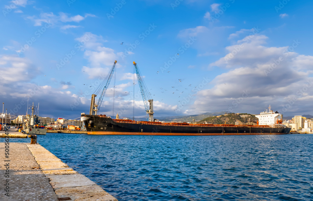 View of the port with a long industrial boat and cranes